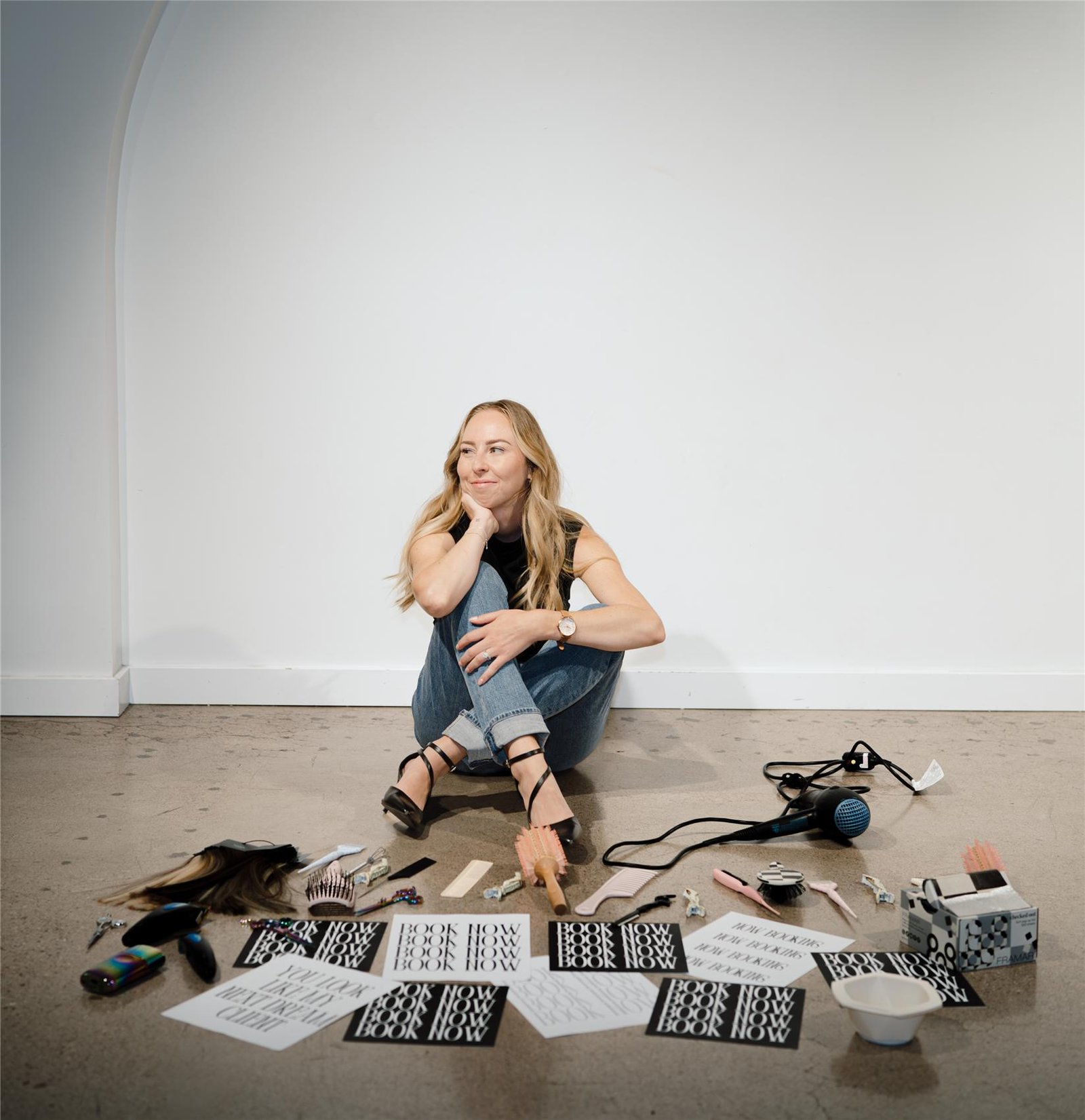 Lillie sitting on the floor surrounded by Hair by Lillie prints and styling tools