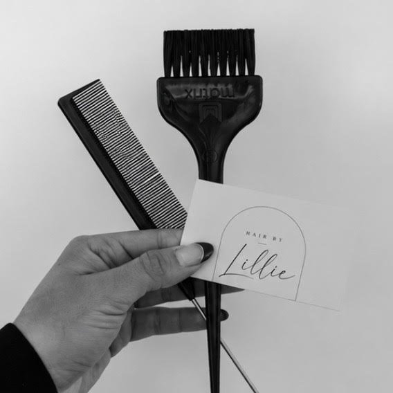 Stylist holding a comb and tint brush with a Hair by Lillie card